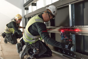 Tuulettuvan julkisivun rangan asennus laser kaksi miestä työkaluja