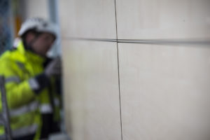 Julkisivun asentaminen loppusuoralla. Viimeistelyä korkeapainelaminaatin reunakiinnitysessä.